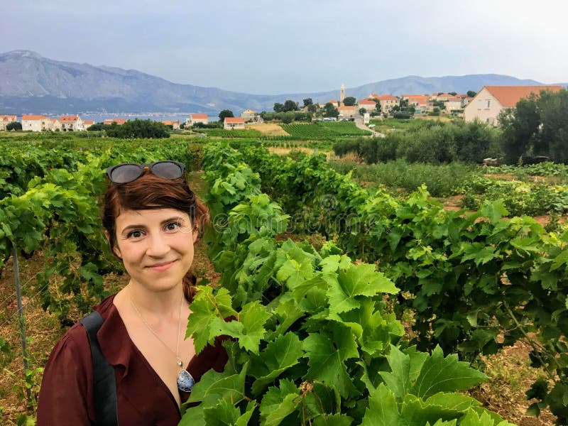 Una situación feliz de la mujer joven entre el viñedo de extensión del vino que produce las uvas locales del grk con la pequeña c foto de archivo Una situación feliz de la mujer joven entre el viñedo de extensión del vino que produce las uvas locales del grk con la pequeña c foto de archivo