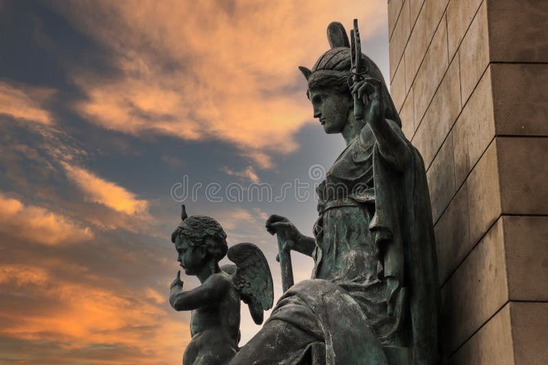 Una statua di una donna e di un bambino contro un muro di pietra marrone circondato da edifici e alberi colorati d'autunno con cielo rosso e potenti nuvole al tramonto al parco della fonderia nel centro di atlanta georgia usa