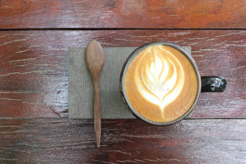 Una taza de café, de capuchino caliente con espuma de la leche y de una cuchara de madera fotos de archivo libres de regalías Una taza de café, de capuchino caliente con espuma de la leche y de una cuchara de madera fotos de archivo libres de regalías