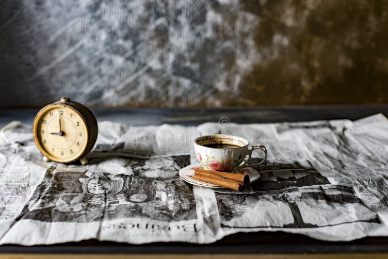una taza de café con un despertador en un periódico viejo fotos de archivo libres de regalías una taza de café con un despertador en un periódico viejo fotos de archivo libres de regalías