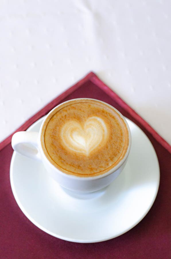 Una taza de capuchino con una espuma y un modelo en forma de corazón foto de archivo Una taza de capuchino con una espuma y un modelo en forma de corazón foto de archivo