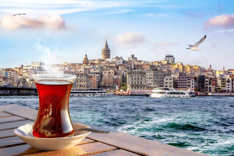 Una taza de té turco en un vidrio tradicional contra la perspectiva del cuerno de oro y de la torre de Galata en Estambul fotografía de archivo libre de regalías Una taza de té turco en un vidrio tradicional contra la perspectiva del cuerno de oro y de la torre de Galata en Estambul fotografía de archivo libre de regalías