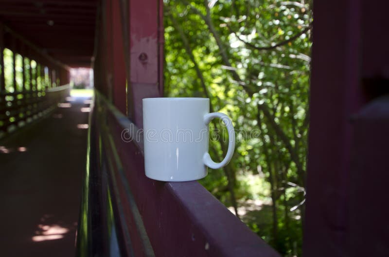 Una taza en blanco a solas del café con leche a lo largo de un puente foto de archivo Una taza en blanco a solas del café con leche a lo largo de un puente foto de archivo