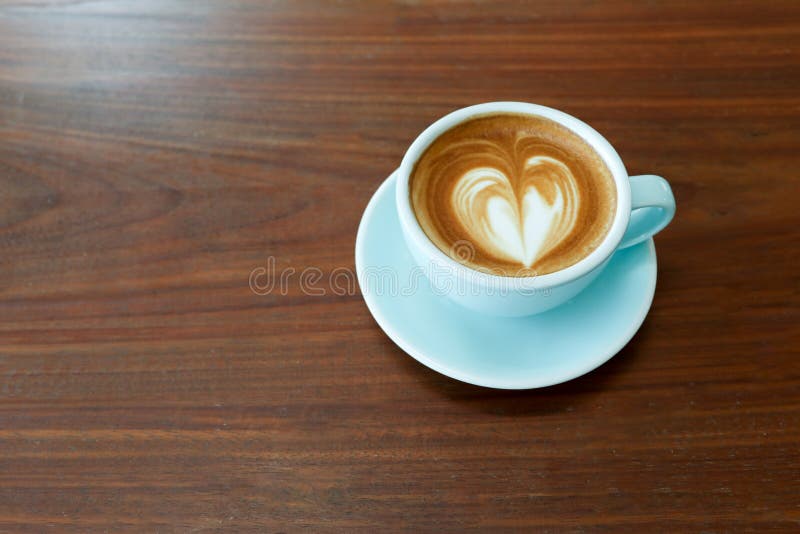 Una tazza del caffè caldo del latte con arte del latte di forma del cuore sulla tavola di legno di marrone scuro fotografie stock libere da diritti Una tazza del caffè caldo del latte con arte del latte di forma del cuore sulla tavola di legno di marrone scuro fotografie stock libere da diritti