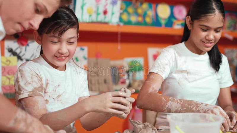 Una tazza di argilla per modellare una ragazza mentre guarda un ragazzo intelligente alla classe d'arte. costruzione