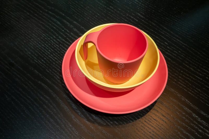 Una tazza di plastica rossa e gialla e lavata sul tavolo nero fotografie stock libere da diritti