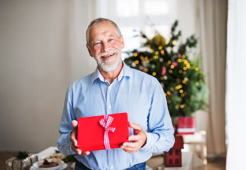 Una tenuta dell'uomo senior ha avvolto presente a tempo di Natale immagini stock libere da diritti Una tenuta dell'uomo senior ha avvolto presente a tempo di Natale immagini stock libere da diritti