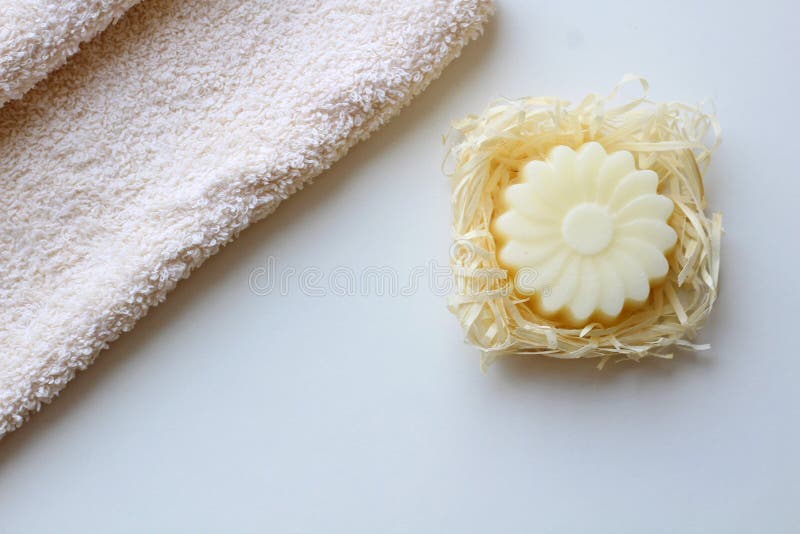Una toalla beige y un jab?n bajo la forma de flor en un fondo ligero Visi?n superior foto de archivo Una toalla beige y un jab?n bajo la forma de flor en un fondo ligero Visi?n superior foto de archivo
