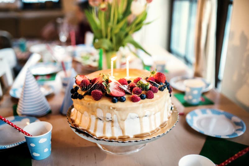 Una torta di compleanno su un supporto di vetro e un vaso con i tulipani sulla tavola fotografie stock Una torta di compleanno su un supporto di vetro e un vaso con i tulipani sulla tavola fotografie stock