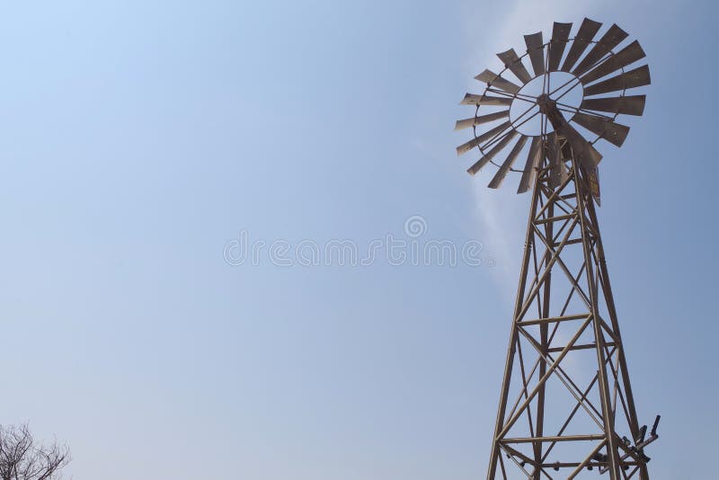 Una vecchia siluetta del mulino a vento con luminoso e cielo blu Bella icona americana della campagna immagini stock libere da diritti Una vecchia siluetta del mulino a vento con luminoso e cielo blu Bella icona americana della campagna immagini stock libere da diritti