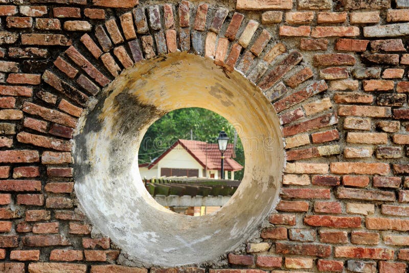 Una vista della casa attraverso una feritoia del cannone nell'isola di Pangkor forte olandese fotografie stock Una vista della casa attraverso una feritoia del cannone nell'isola di Pangkor forte olandese fotografie stock