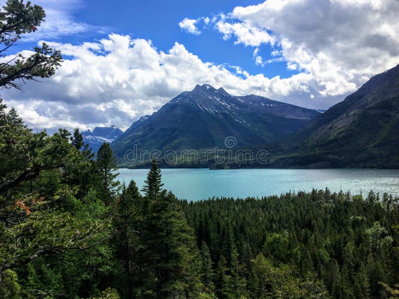 Una vista di un lago maestoso del turchese circondato dalle vaste foreste e montagne sempreverdi verdi un giorno soleggiato con c immagini stock libere da diritti Una vista di un lago maestoso del turchese circondato dalle vaste foreste e montagne sempreverdi verdi un giorno soleggiato con c immagini stock libere da diritti