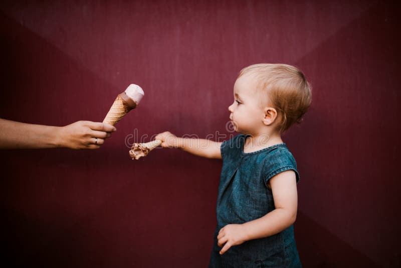 Una vista lateral de la pequeña niña pequeña al aire libre en verano, comiendo el helado fotografía de archivo Una vista lateral de la pequeña niña pequeña al aire libre en verano, comiendo el helado fotografía de archivo
