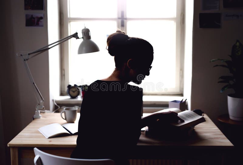 Una vista posterior del estudiante joven que se sienta en la tabla, estudiando fotografía de archivo Una vista posterior del estudiante joven que se sienta en la tabla, estudiando fotografía de archivo
