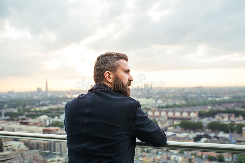 Una vista posterior el hombre de negocios que se opone a panorama de la opinión de Londres imagen de archivo libre de regalías Una vista posterior el hombre de negocios que se opone a panorama de la opinión de Londres imagen de archivo libre de regalías