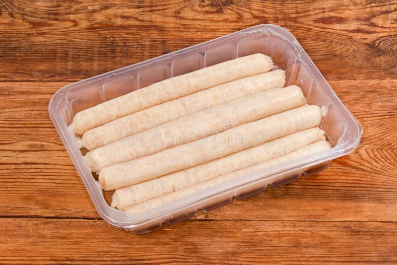 Uncooked Chicken Sausages in Plastic Container on a Rustic Table Stock