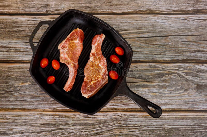 Uncooked pork loin chops in grill skillet with tomatoes