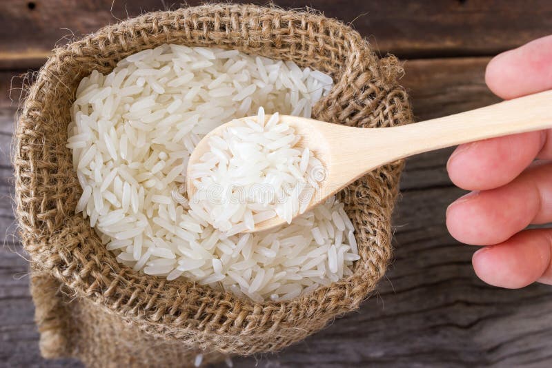 Uncooked rice in a wooden spoon over small burlap sack. stock image Uncooked rice in a wooden spoon over small burlap sack. stock image