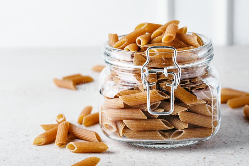 Uncooked whole grain pasta. In a glass jar stock photos