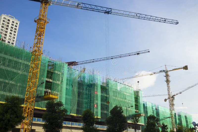 Under Construction Buildings with Cranes Working on Blue Sky Stock