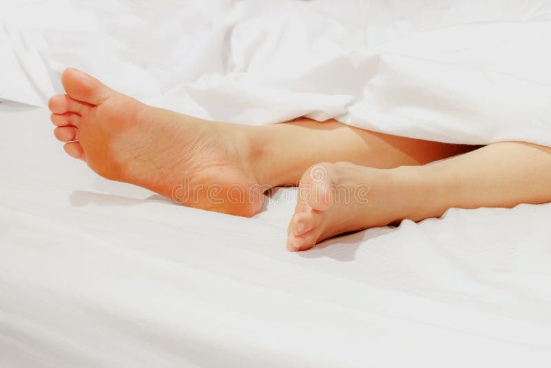 Under the Covers with Feet Showing in a Bed. Stock Photo Image of