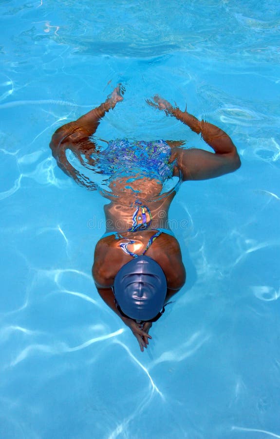 Young girl swimming underwater creating a symmetrical design. Young girl swimming underwater creating a symmetrical design.