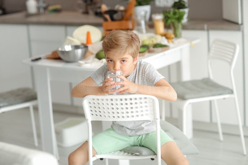 Underbart barn 8 år sitter på en stol och ser ut att vara med i kameran fotografering för bildbyråer