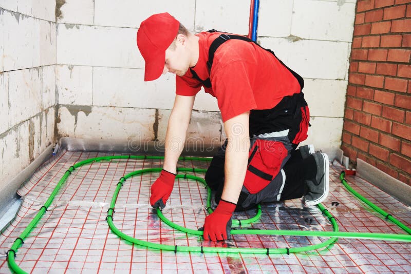 Floor heating system. Pipe fitter mounting underfloor heating. Heating system with hot water circulation in pipes. Floor heating system. Pipe fitter mounting underfloor heating. Heating system with hot water circulation in pipes