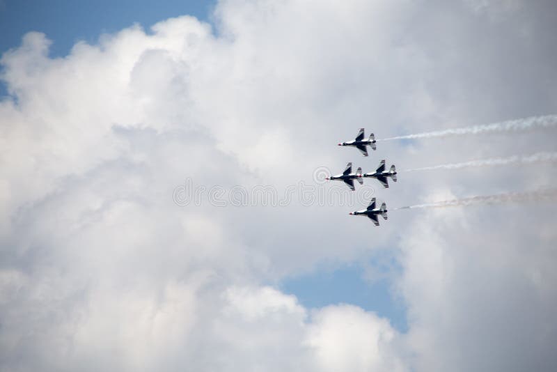 The underside of four USAF Thunderbirds against a cloudy sky, trailing smoke. The underside of four USAF Thunderbirds against a cloudy sky, trailing smoke.