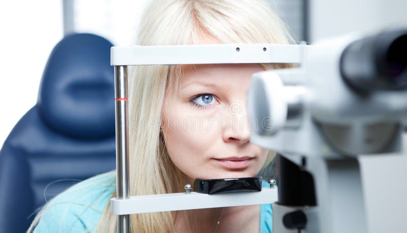 Optometry concept - pretty young woman having her eyes examined by an eye doctor on a slit lamp. Optometry concept - pretty young woman having her eyes examined by an eye doctor on a slit lamp