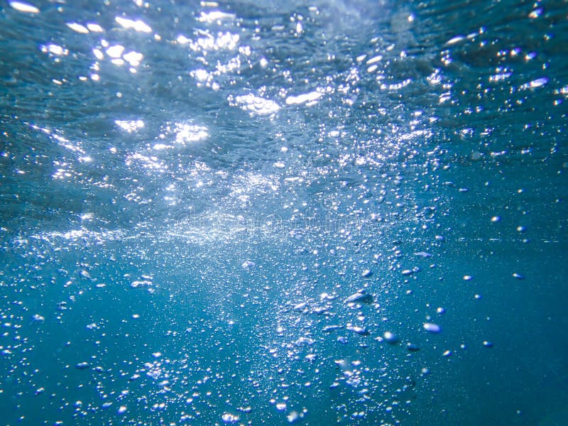 Sea Bubbles . Blue Sea Waves from Underwater with Bubbles. Light Rays