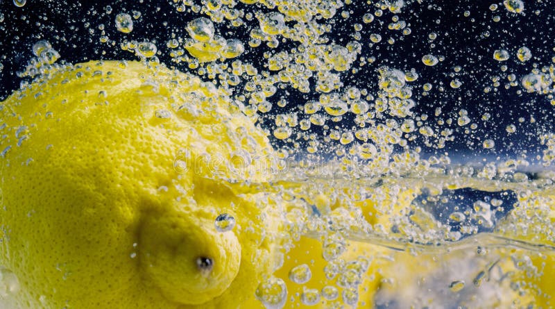 Underwater lemon slice in soda water or lemonade with bubbles royalty free stock photos