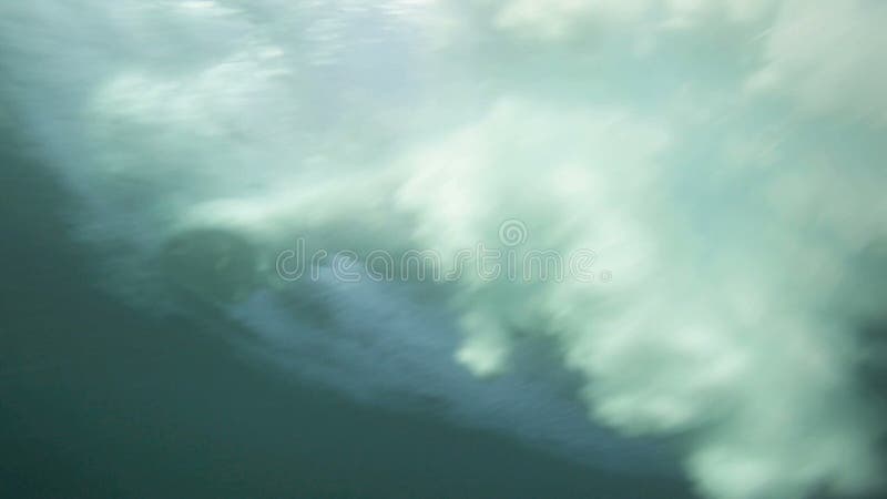 Underwater view of surfing and breaking waves over tropical coral reef
