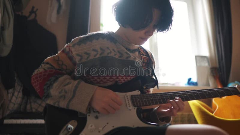 Une adolescente joue de la guitare électrique dans sa chambre. concept de rêve de musique familiale heureuse. adolescente guitaris banque de vidéos