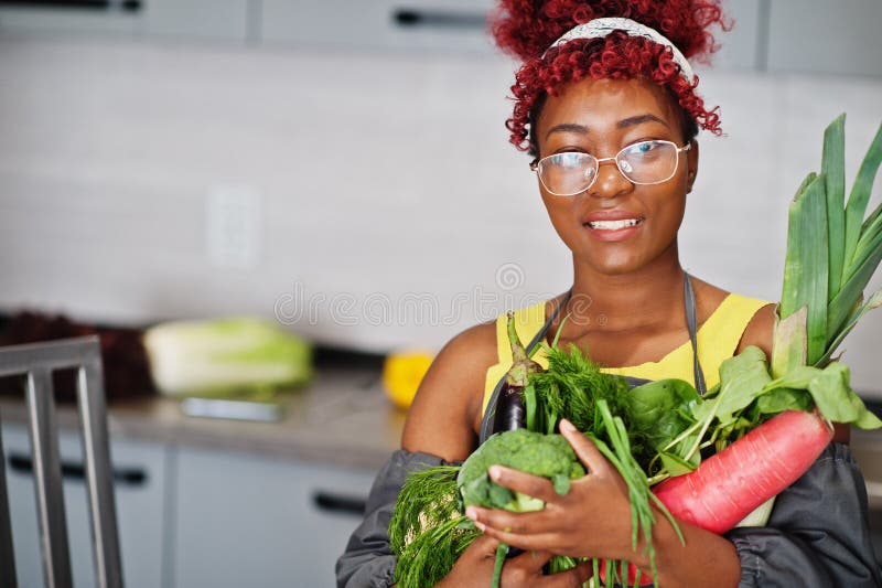 Une afro-américaine filmant son blog a diffusé un reportage sur la nourriture saine à la maison. elle tient les légumes à la main photo libre de droits