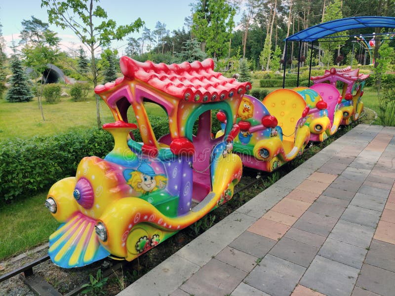 Brightly painted children's locomotive attraction with carriages in an amusement park. Brightly painted children's locomotive attraction with carriages in an amusement park