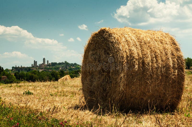 Une balle de paille sous le soleil d'été sur l'horizon les tours de San Gimignano photo stock Une balle de paille sous le soleil d'été sur l'horizon les tours de San Gimignano photo stock