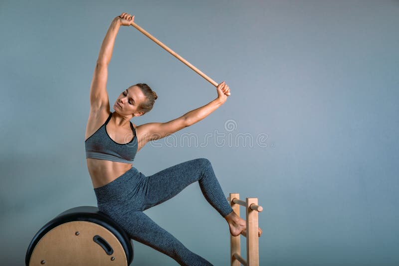 Une belle femme blonde positive est en train d'être préparée à faire des exercices de pilates, à la formation sur l'équipement en images libres de droits