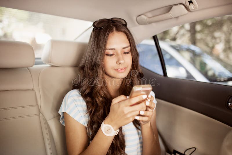 Une belle fille aux cheveux foncés mince avec des verres, style occasionnel de port, regarde l'écran et le sourire photo stock Une belle fille aux cheveux foncés mince avec des verres, style occasionnel de port, regarde l'écran et le sourire photo stock