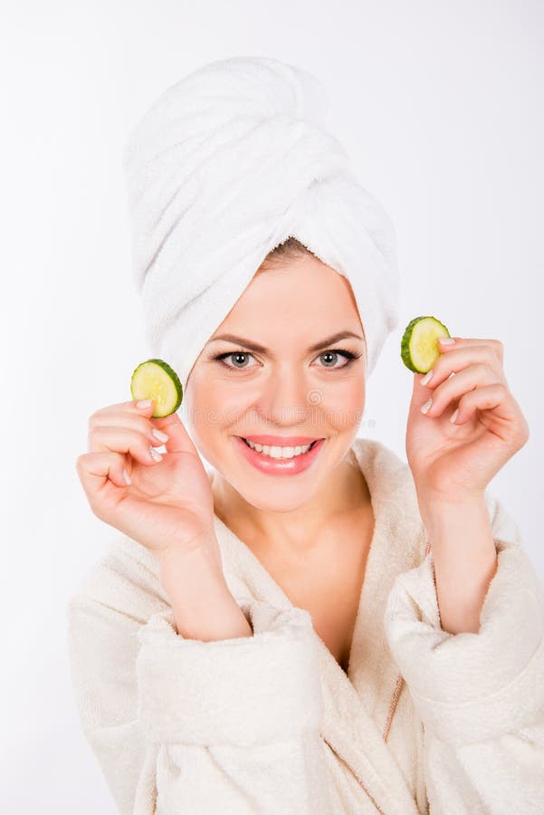 Une belle jeune fille avec des tranches de concombre pour son visage image stock