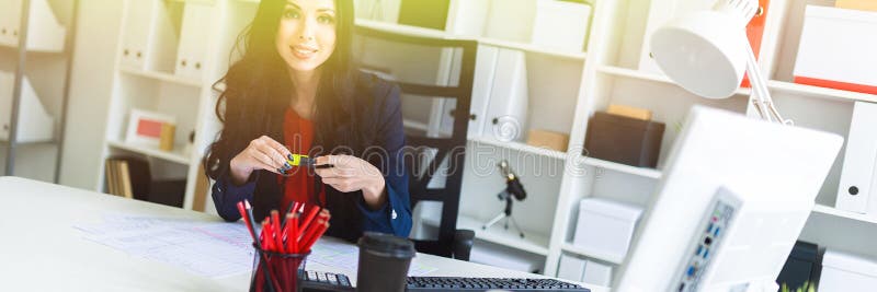 Une belle jeune fille s'assied dans le bureau à la table et tient un marqueur jaune dans des ses mains image libre de droits Une belle jeune fille s'assied dans le bureau à la table et tient un marqueur jaune dans des ses mains image libre de droits
