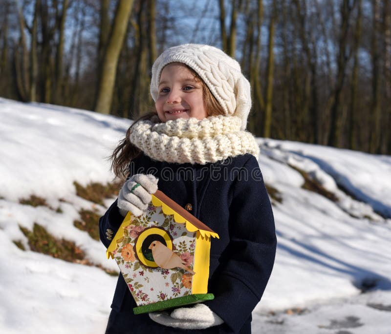 Une belle petite fille de sourire tenant une maison d'oiseau en parc photo libre de droits Une belle petite fille de sourire tenant une maison d'oiseau en parc photo libre de droits