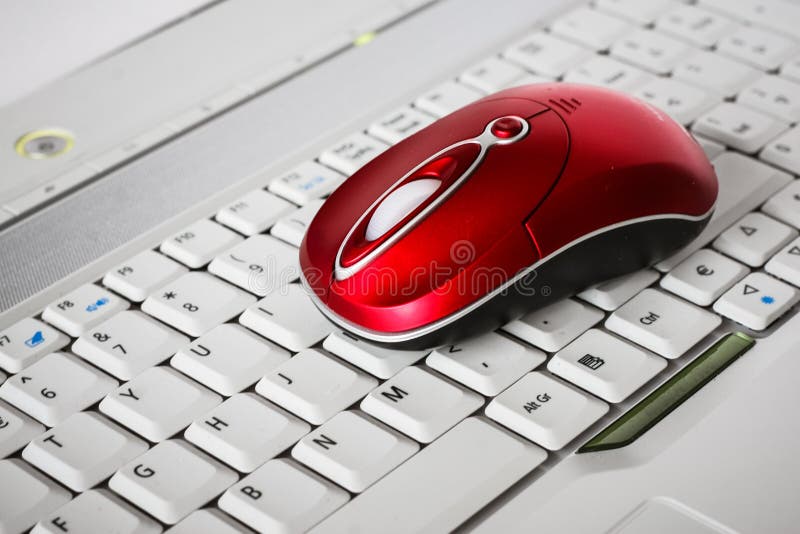 Une belle souris sans fil rouge sur le clavier blanc d'un ordinateur portable photo stock Une belle souris sans fil rouge sur le clavier blanc d'un ordinateur portable photo stock