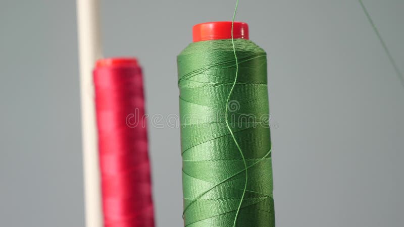 Une bobine de fil rouge et vert de coton sur l'axe de la machine? coudre dans le premier plan, plan rapproch? Usine de couture banque de vidéos