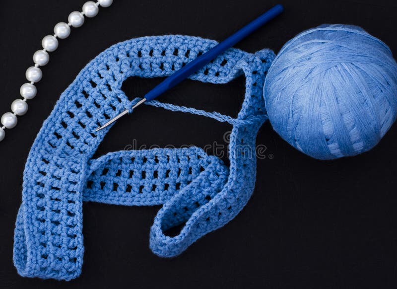 Une boule de fil bleu avec un crochet sur un fond noir photographie stock Une boule de fil bleu avec un crochet sur un fond noir photographie stock