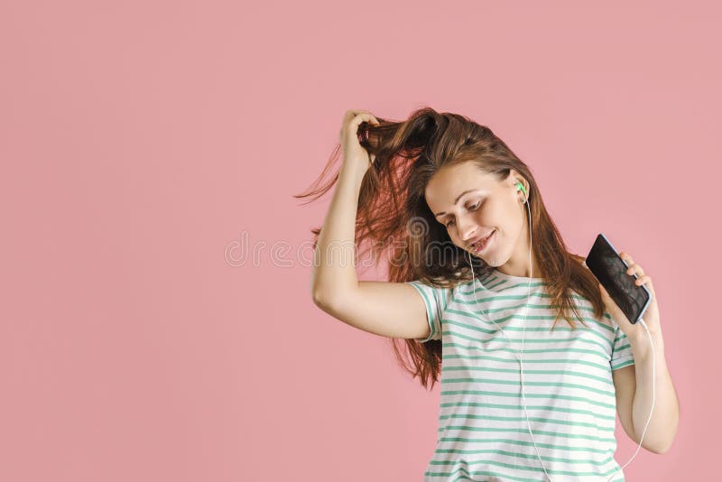 Une charmante brune d'âge moyen danse en écoutant de la musique grâce aux écouteurs d'un smartphone. espace de copie photo stock
