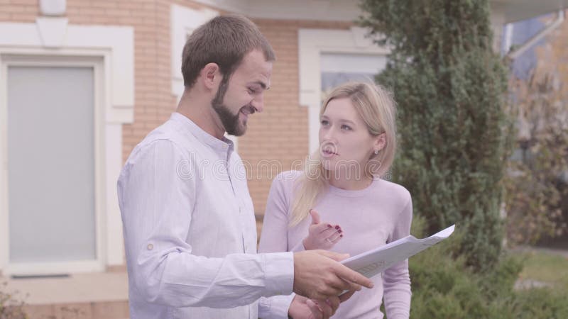 Une cliente caucasienne insatisfaite discutant du projet avec une créatrice Architecte barbu expliquant les dessins aux banque de vidéos