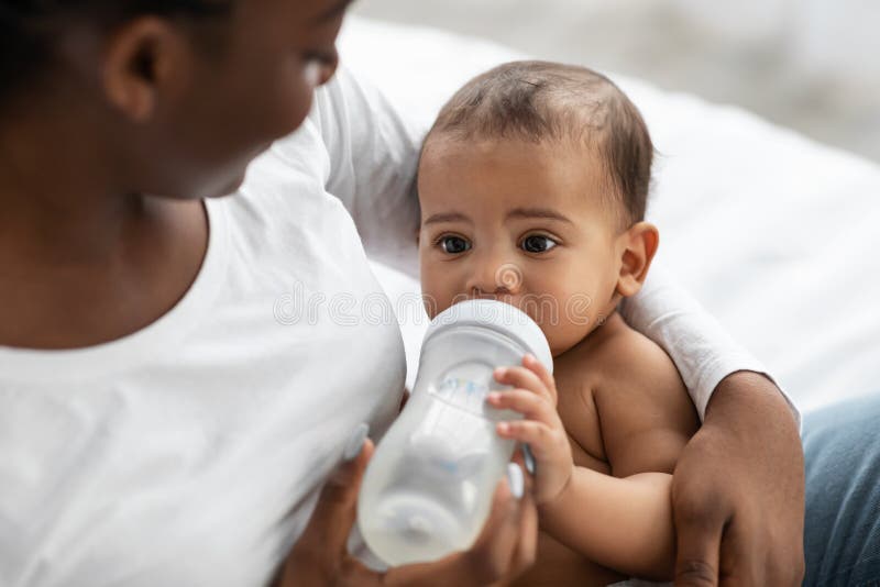 Une dame afro-américaine nourrit son enfant avec un biberon