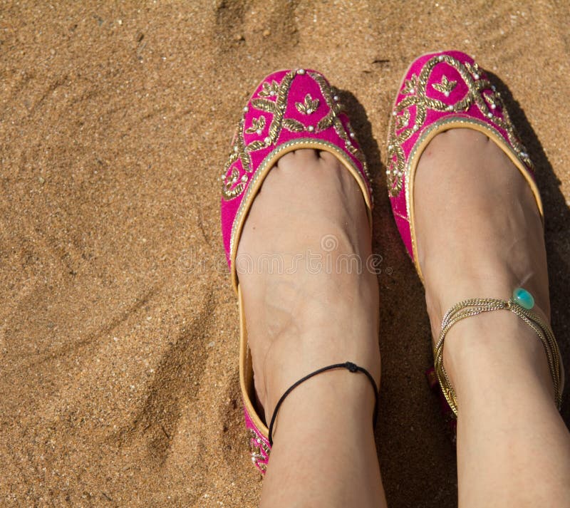 Une dame portant une paire de ` indien traditionnel rose s de femmes chausse des jutis à la plage d'Anjuna dans Goa, Inde photographie stock Une dame portant une paire de ` indien traditionnel rose s de femmes chausse des jutis à la plage d'Anjuna dans Goa, Inde photographie stock
