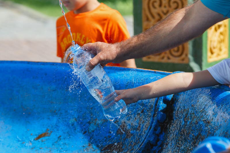 Une famille chrétienne versant l'eau sainte dans une bouteille du ressort saint photos libres de droits Une famille chrétienne versant l'eau sainte dans une bouteille du ressort saint photos libres de droits